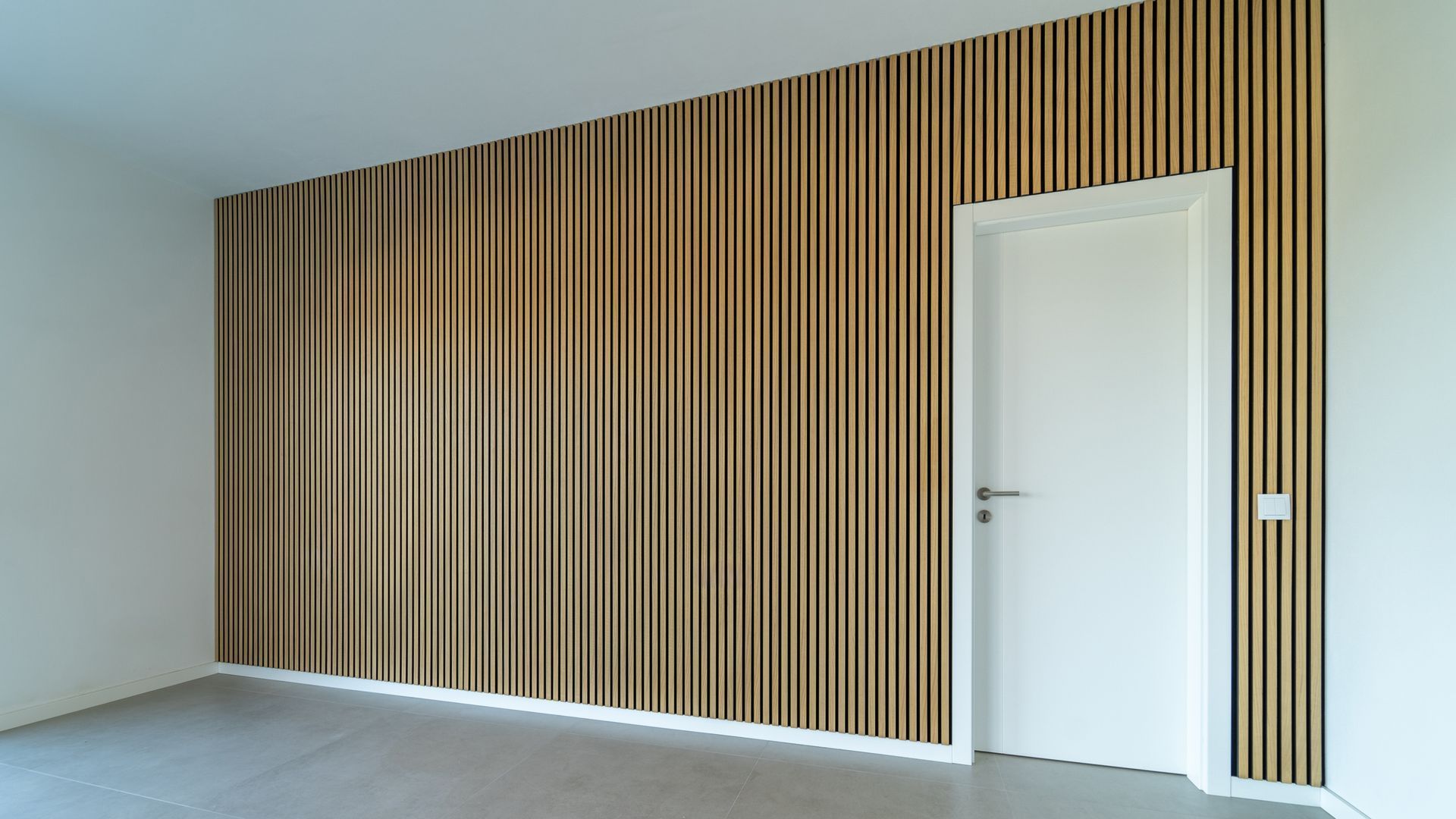 An empty room with a wooden wall and a white door.