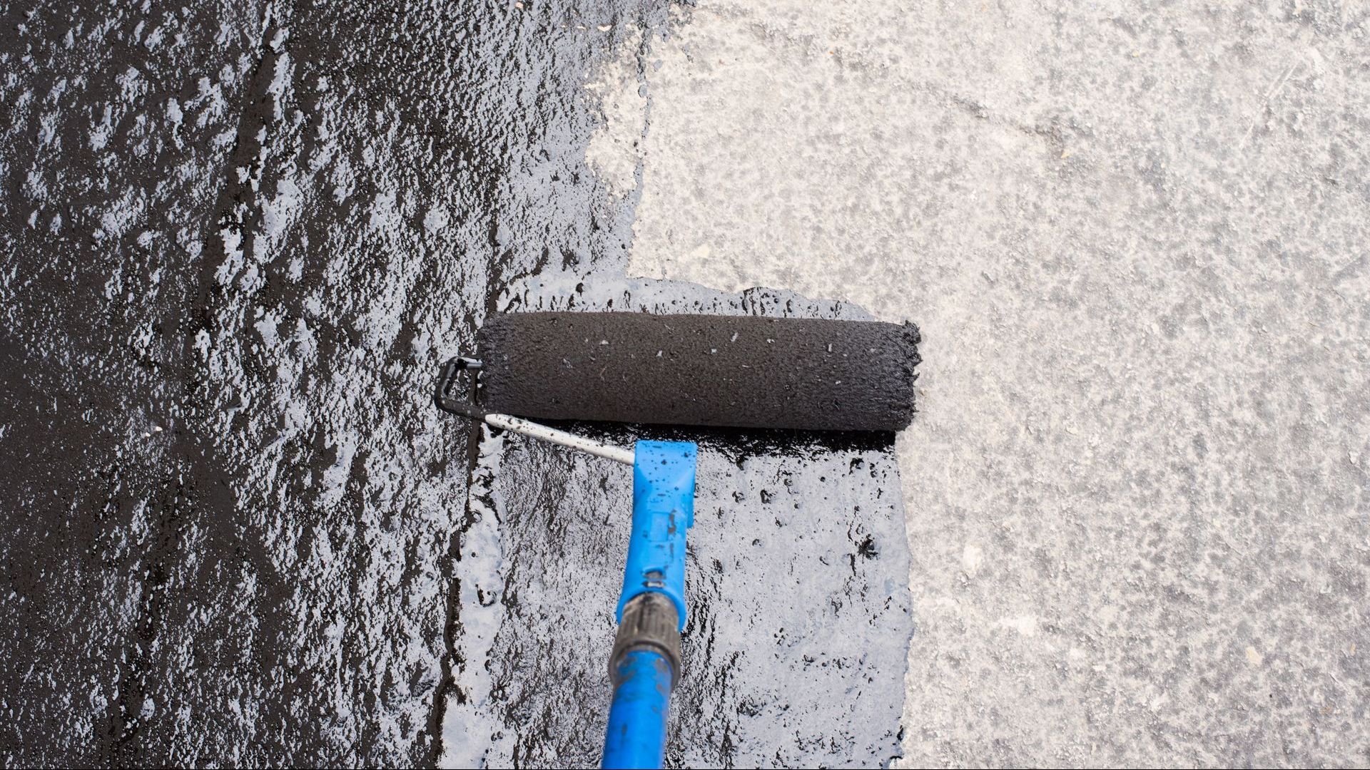 A roller is being used to paint a concrete surface.