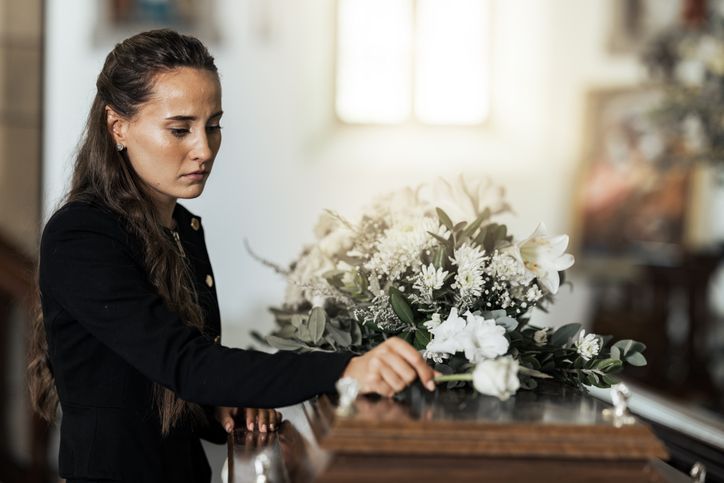 Funeral, sad and woman with flower on coffin after loss of a loved one
