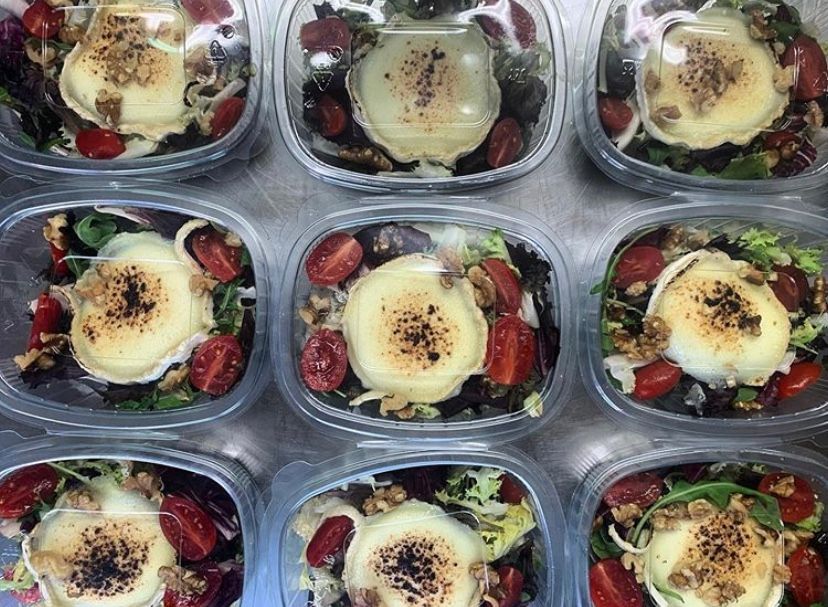 A bunch of plastic containers filled with salads and cheese.