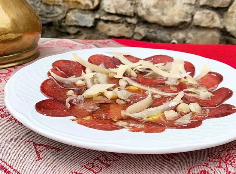 A white plate topped with meat and cheese is on a table.