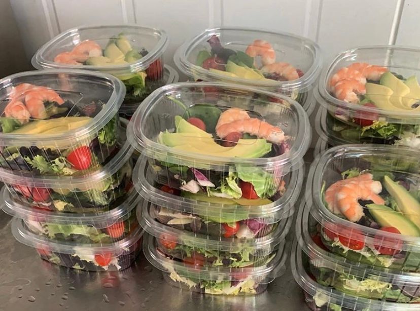 A stack of plastic containers filled with salad and shrimp.