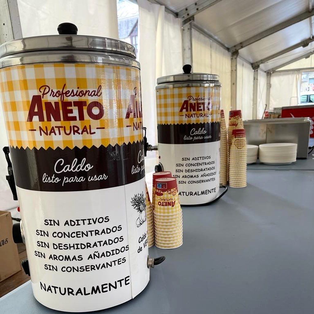 Two containers of aneto natural caldo are sitting on a table.