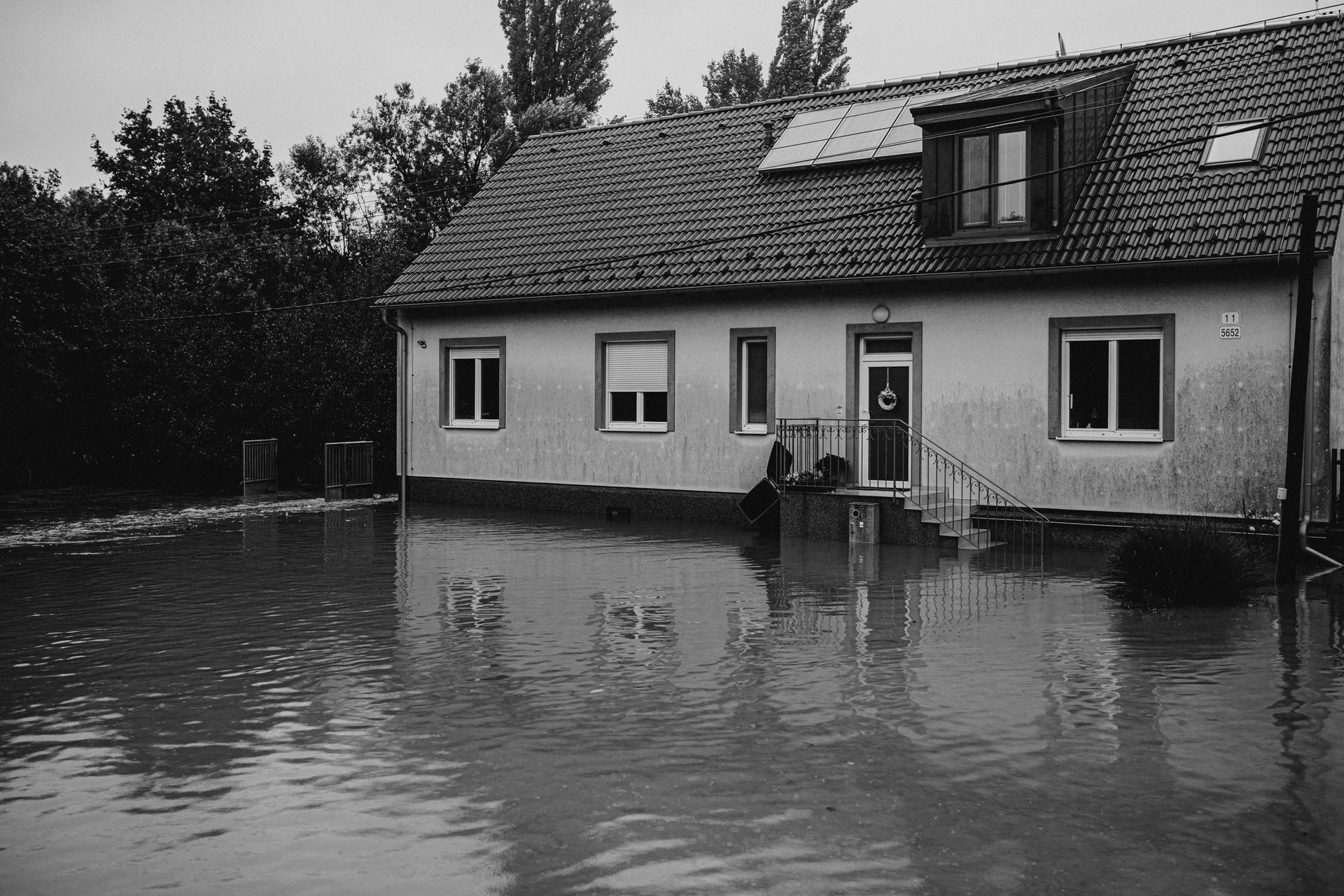 Flooded home with water reaching the front steps, showing storm damage to residential property