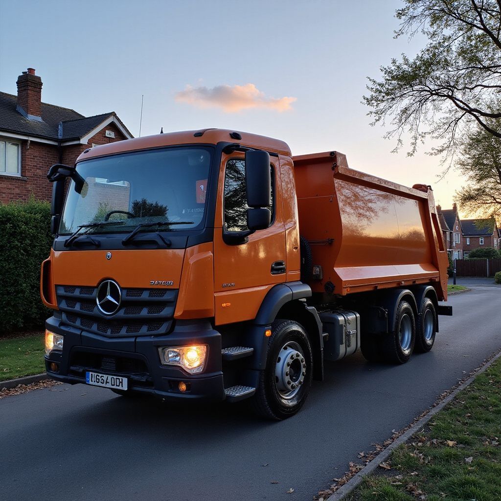 Orange dump truck parked on a residential street at dusk.
