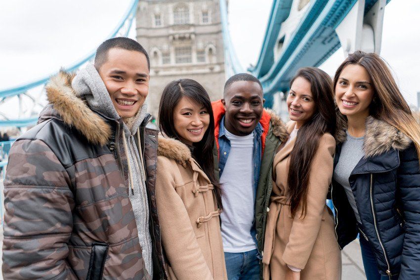 Happy group of tourists sightseeing in London near Tower Bridge