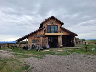 A large wooden barn is sitting in the middle of a grassy field.