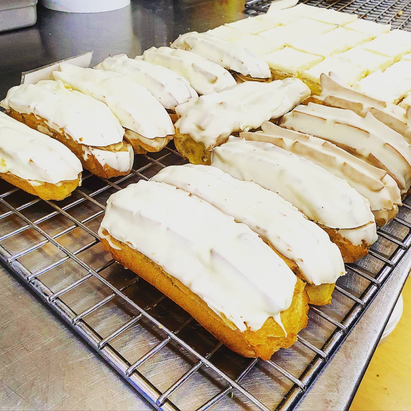 Golden pastries topped with white icing, arranged on a wire rack.— Atherton Bakehouse in Atherton, QLD