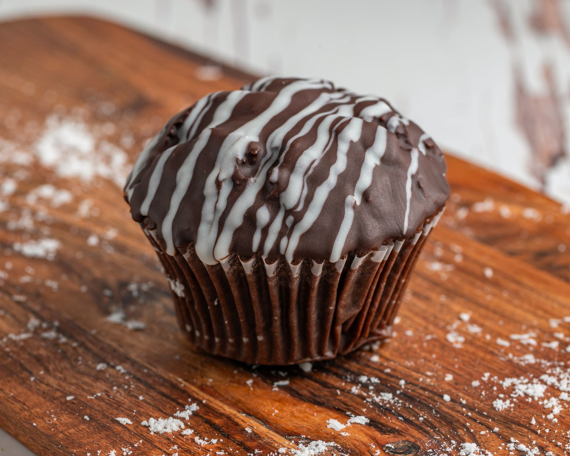 Chocolate Muffin With White Icing Drizzle on a Wooden — Atherton Bakehouse in Atherton, QLD