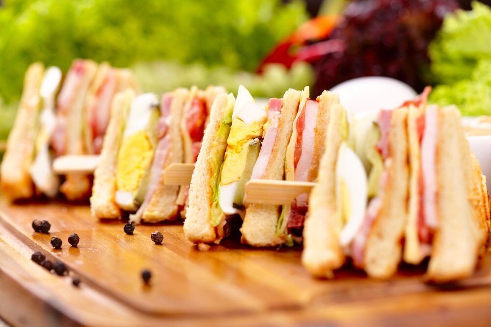 Club sandwiches on a wooden board with lettuce and pepper.— Atherton Bakehouse in Atherton, QLD