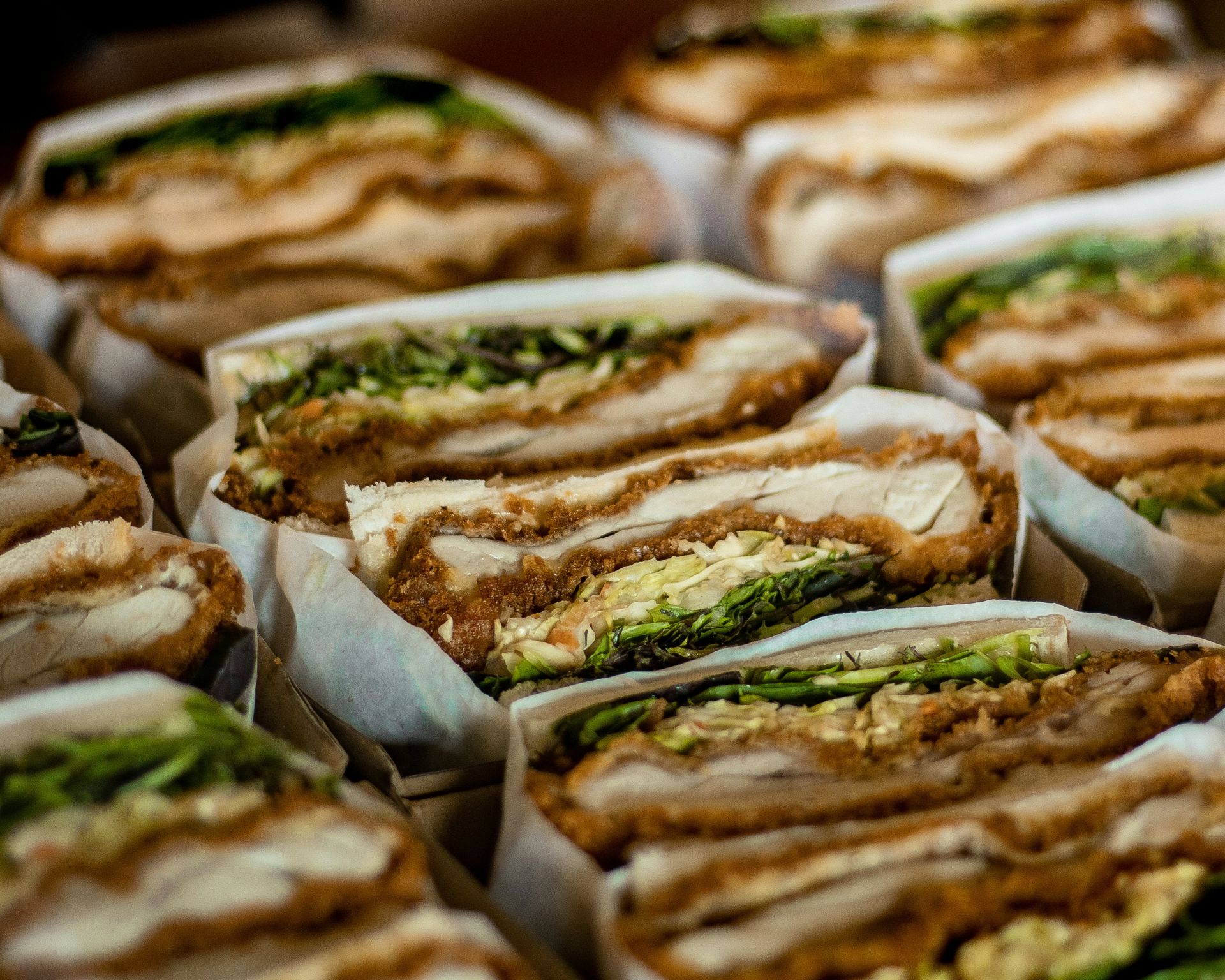 Sandwiches, cut in half, showcasing crispy fried cutlets and lettuce fillings.— Atherton Bakehouse in Atherton, QLD