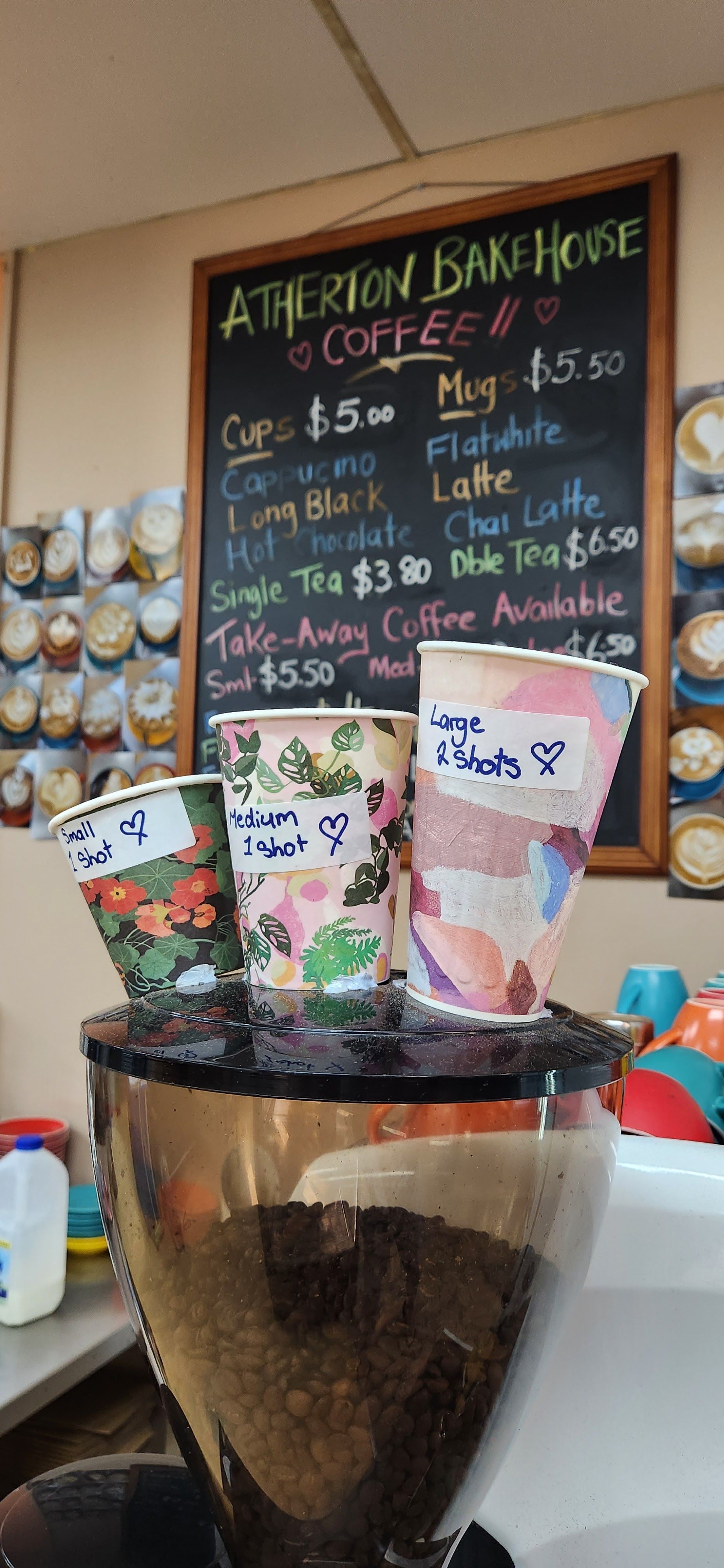 Three Coffee Cups Atop a Coffee Grinder in Front of a Menu Board — Atherton Bakehouse in Atherton, QLD