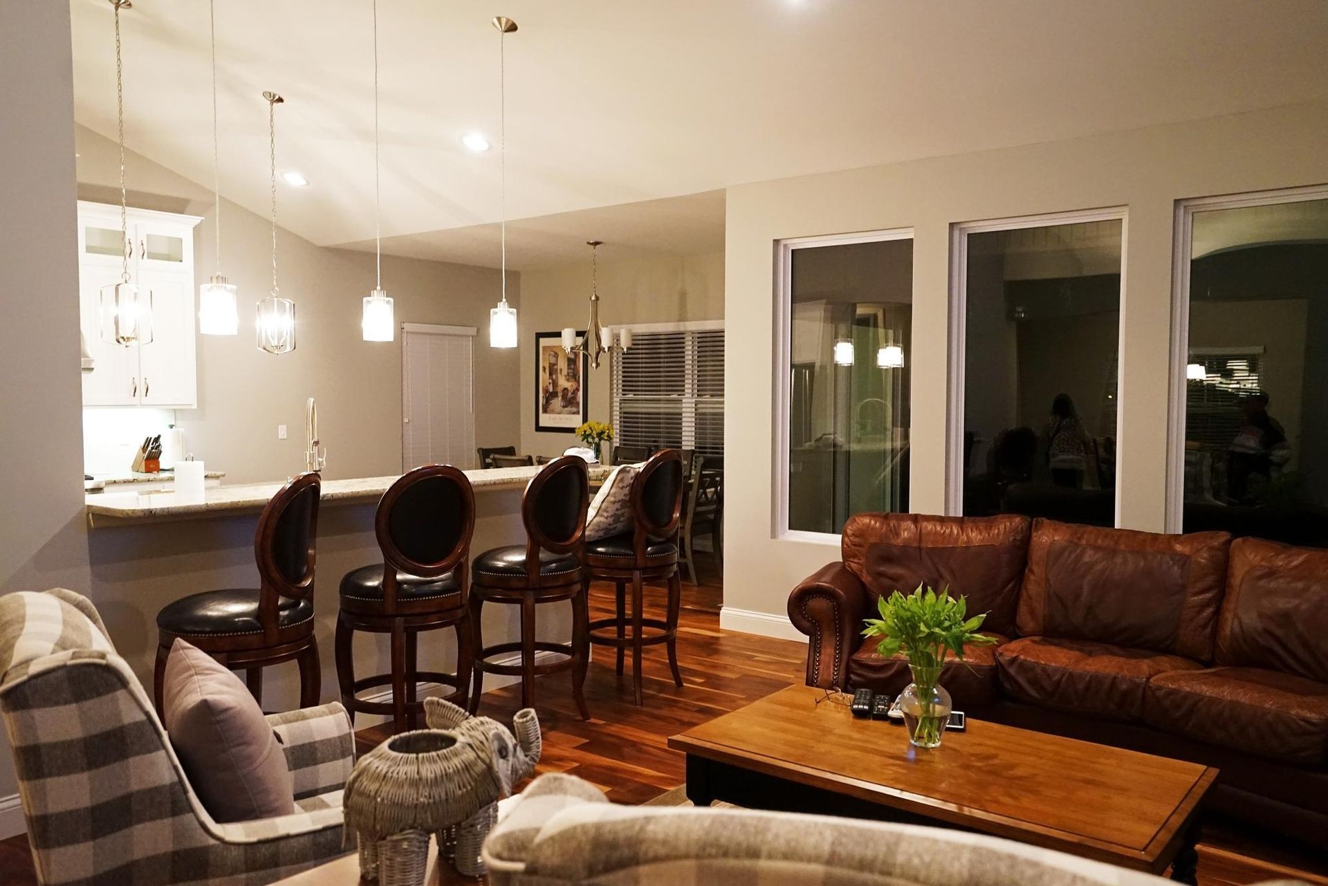Modern kitchen with brown cabinets, white island, and copper pendant lights. Four brown bar stools.