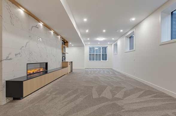 Empty modern living room with fireplace, white walls, and beige carpet.