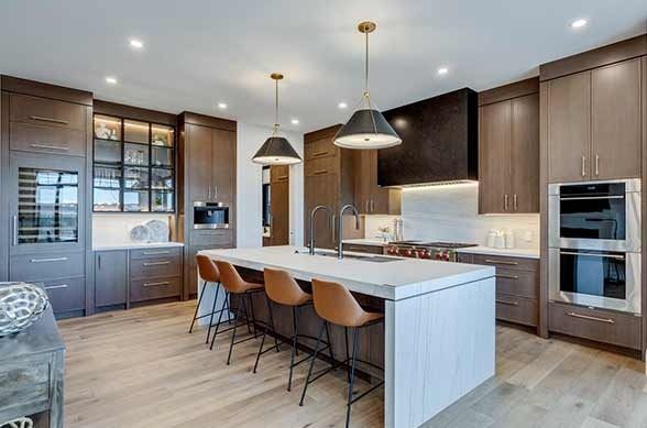 Modern kitchen with brown cabinetry, white island, and leather bar stools.