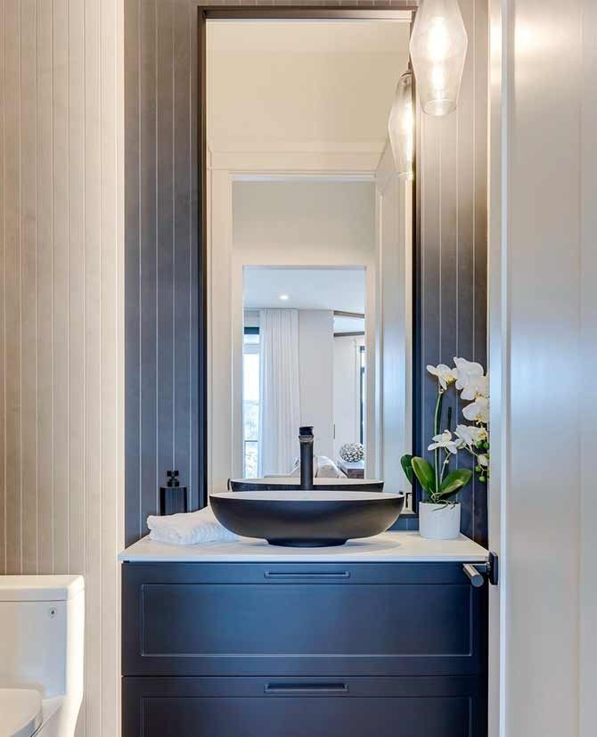 Dark blue vanity with black vessel sink and tall mirror in a modern bathroom.