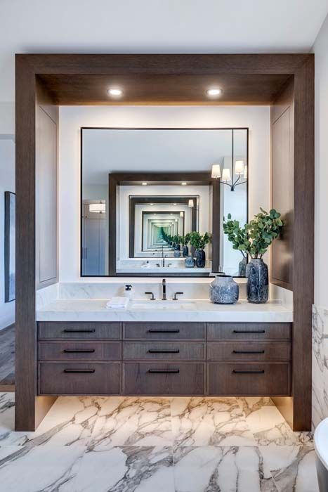 Modern bathroom with a large mirror, dark wood vanity, and marble floors.
