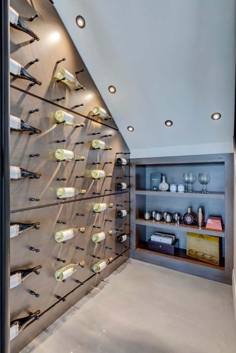 Wine cellar with bottles displayed on a wall-mounted rack, and a built-in shelving unit.