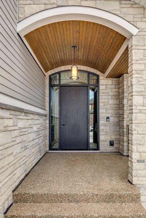 Entryway with stone walls, wooden ceiling, dark door, and two steps.