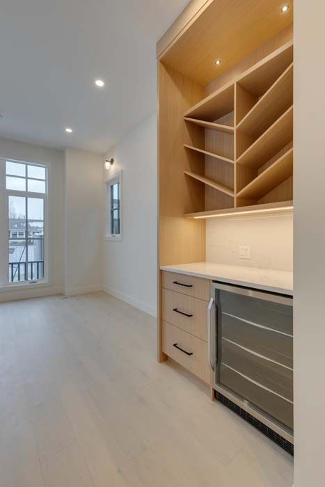 Built-in bar with wine storage, drawers, and mini-fridge in a bright, white room.