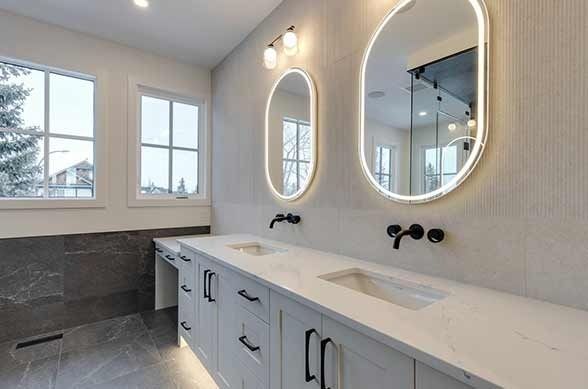Modern bathroom with a white vanity, two oval mirrors, and black fixtures.
