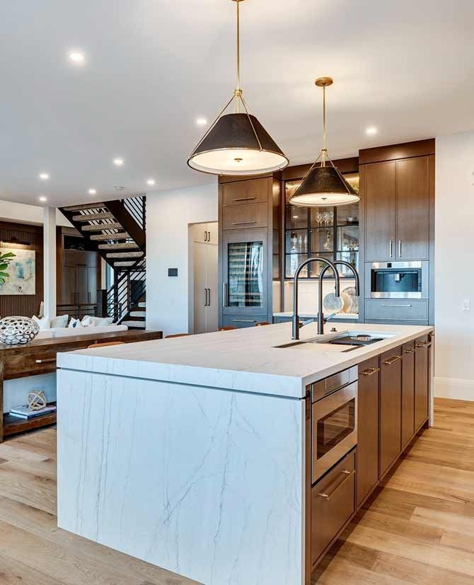 Modern kitchen with island, pendant lights, wooden cabinets, and a microwave.