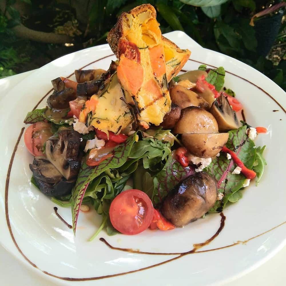 A White Plate Topped With A Salad With Tomatoes And Mushrooms — Vines at 139 in Grafton, NSW