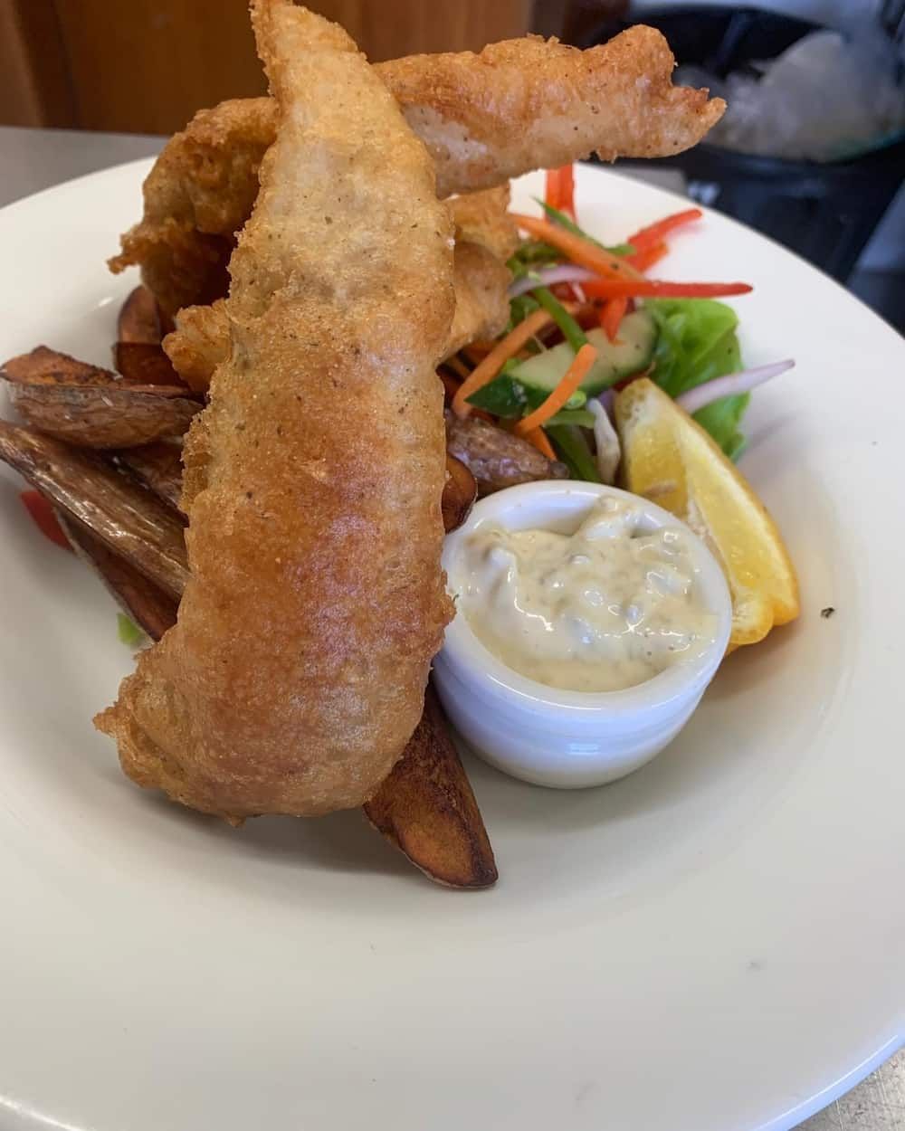 A White Plate Topped With Fried Fish , French Fries , And A Salad — Vines at 139 in Grafton, NSW