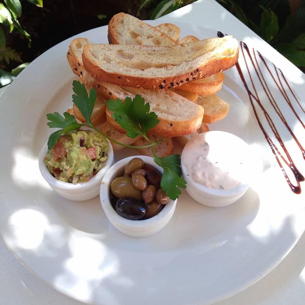 A White Plate Topped With Bread Guacamole And Olives — Vines at 139 in Grafton, NSW