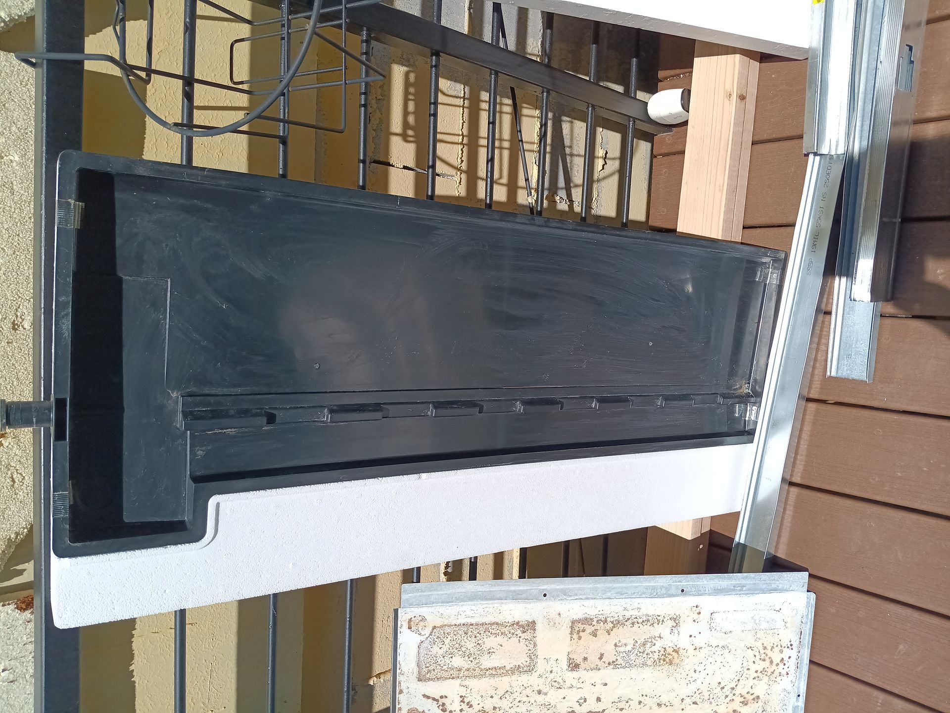 A black planter is sitting on top of a wooden deck