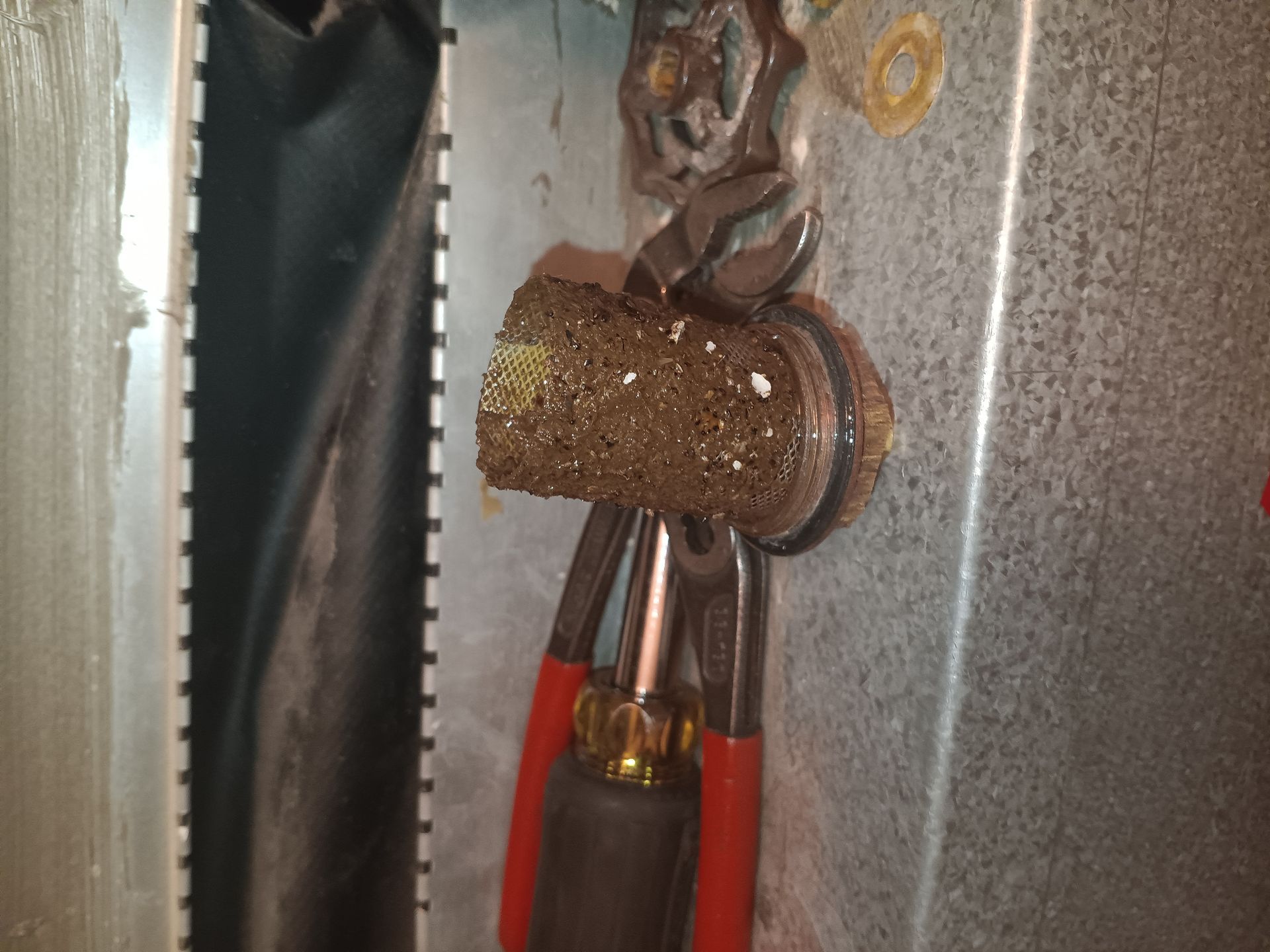 A pair of pliers holding a piece of metal on a metal surface.