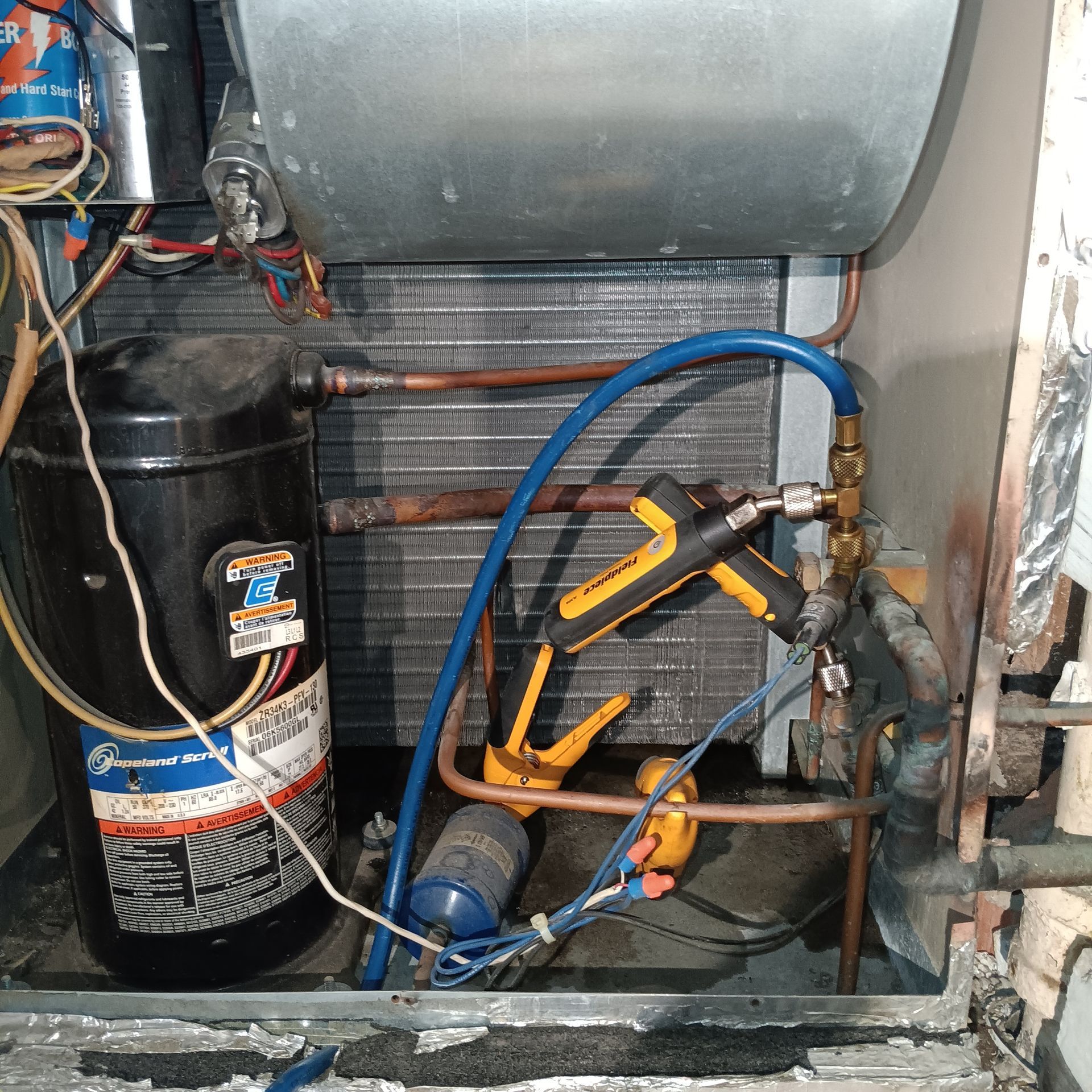 An air conditioner is being worked on with a hose attached to it