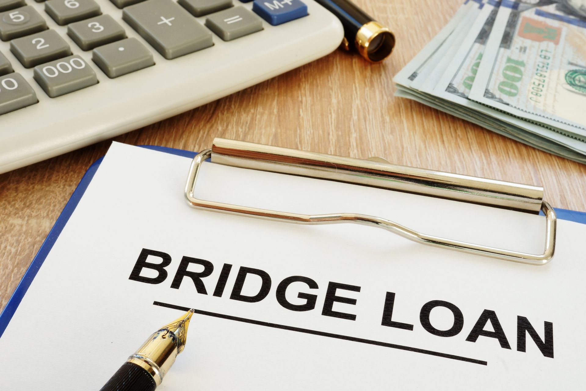 A bridge loan is written on a clipboard next to a pen and calculator.