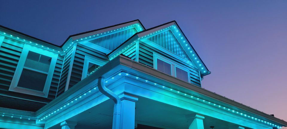 Blue-lit house exterior at dusk, showing peaked roof and porch from a low angle