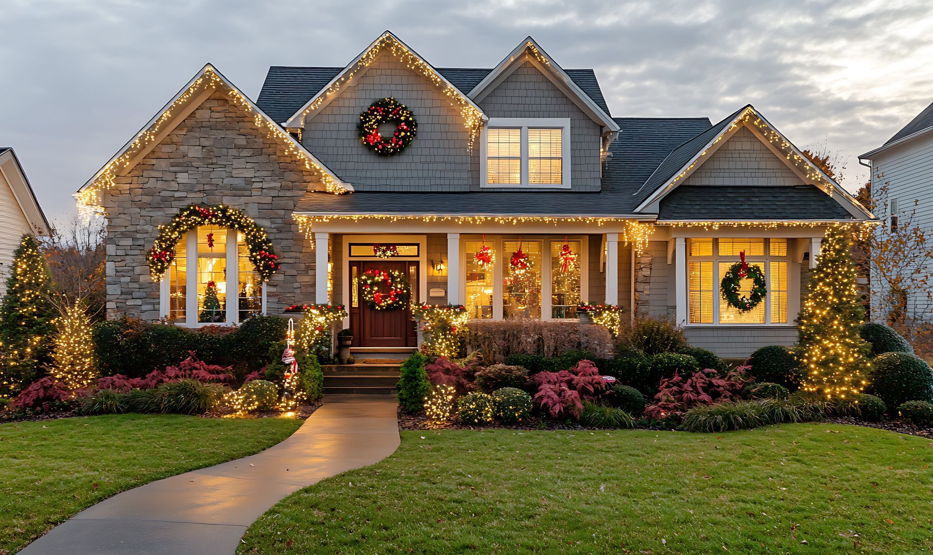 Suburban house at dusk with warm Christmas lights, wreaths, and a lit front walkway