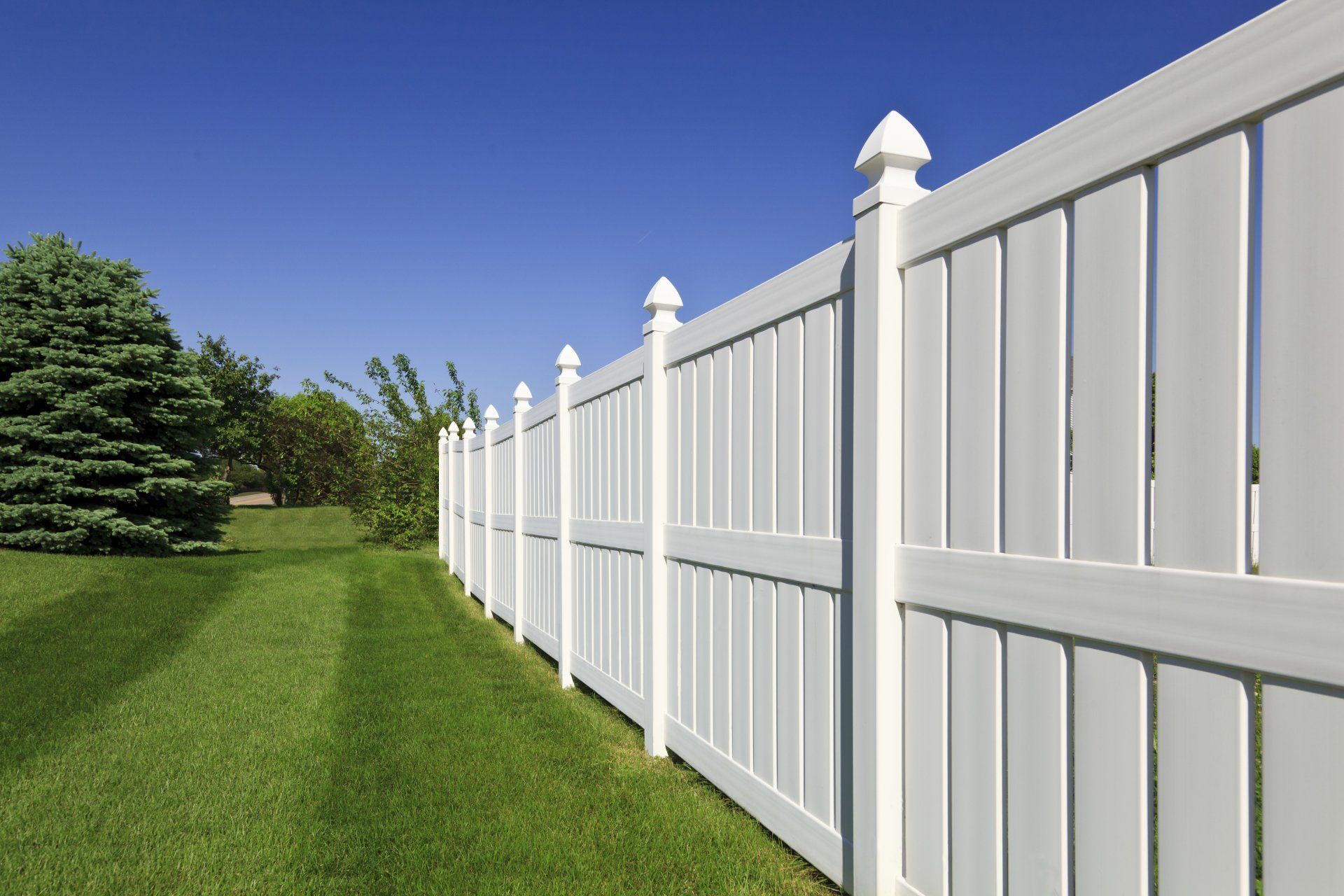 A white fence surrounds a lush green yard
