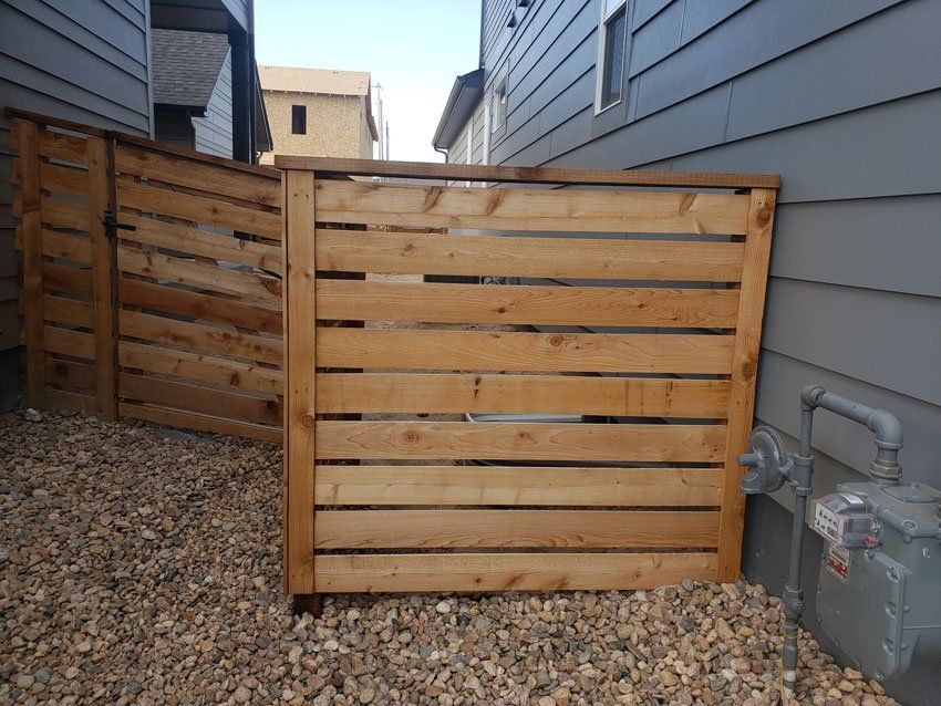 A wooden fence is in the backyard of a house.