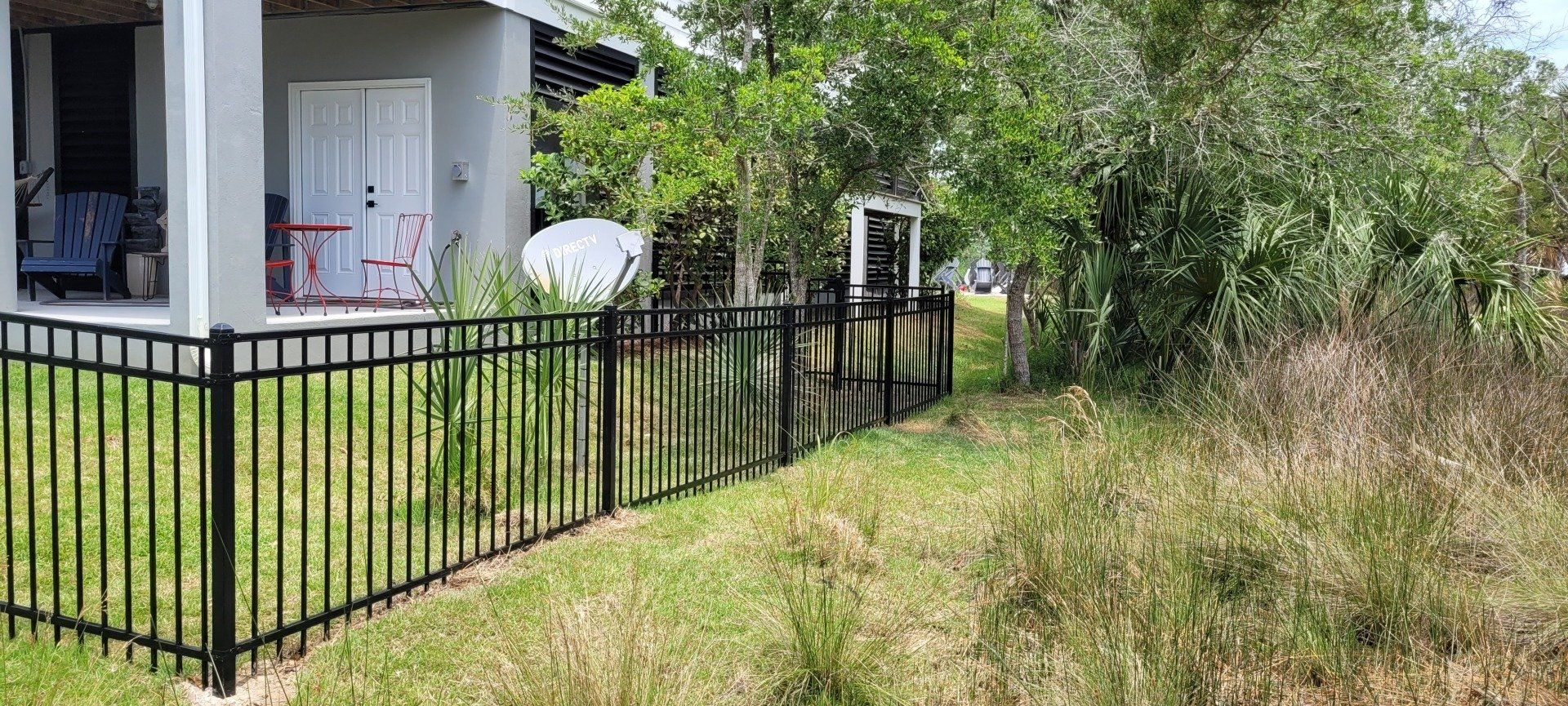A black fence surrounds a small house with a porch.