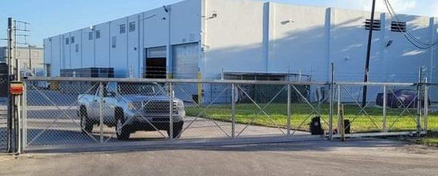 A car is driving through a gate in front of a large building.