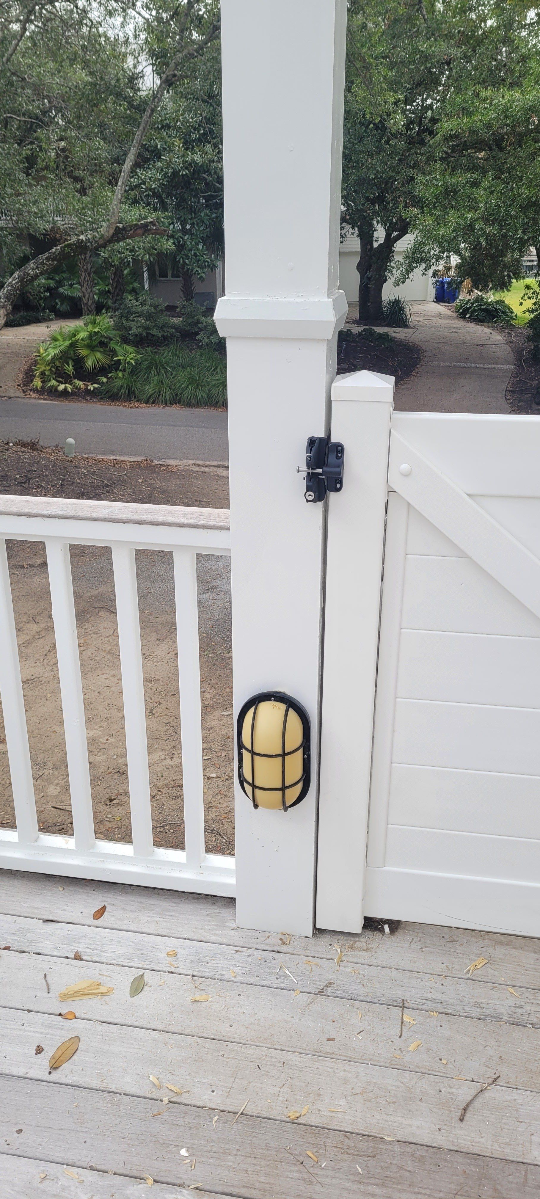 A white post with a light attached to it next to a white gate.