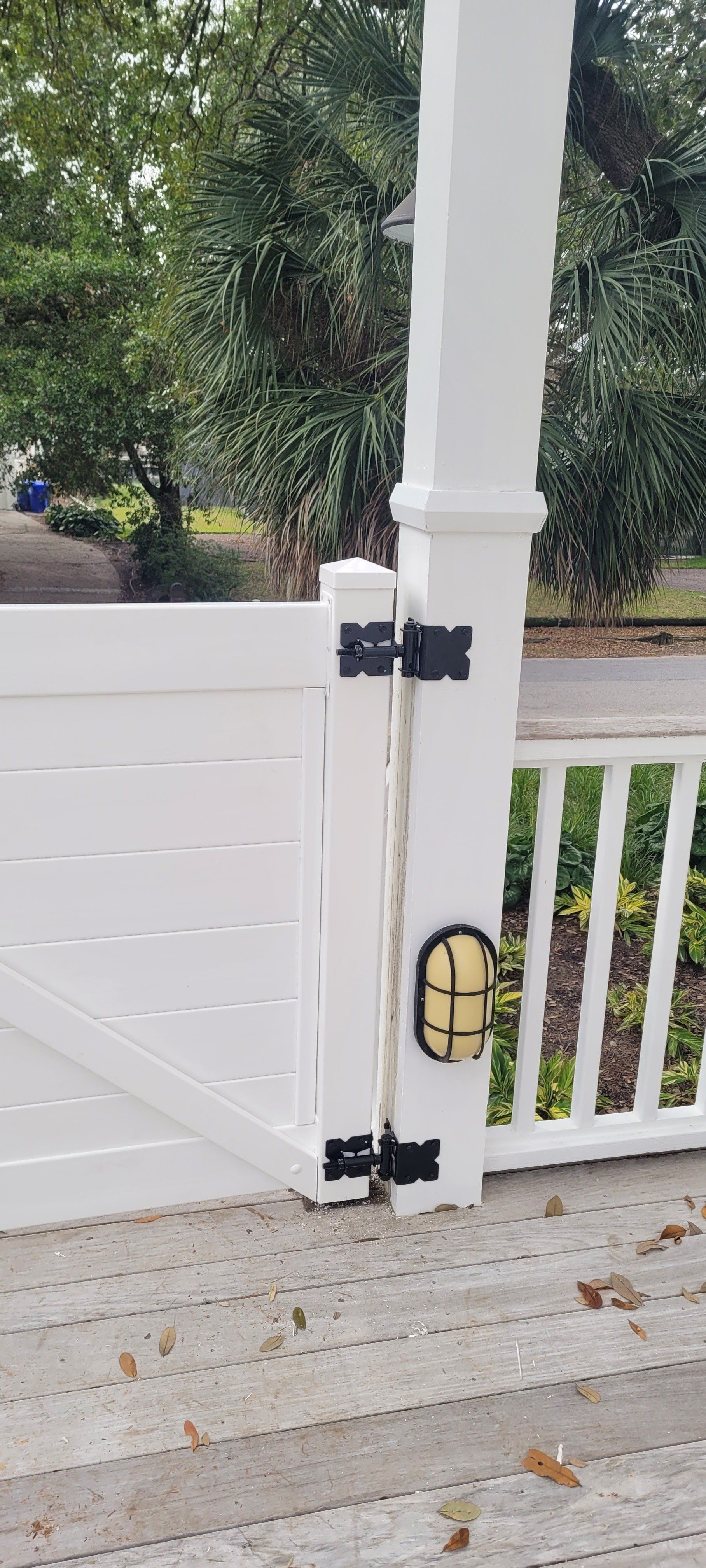 A white fence with a light on it is next to a porch.