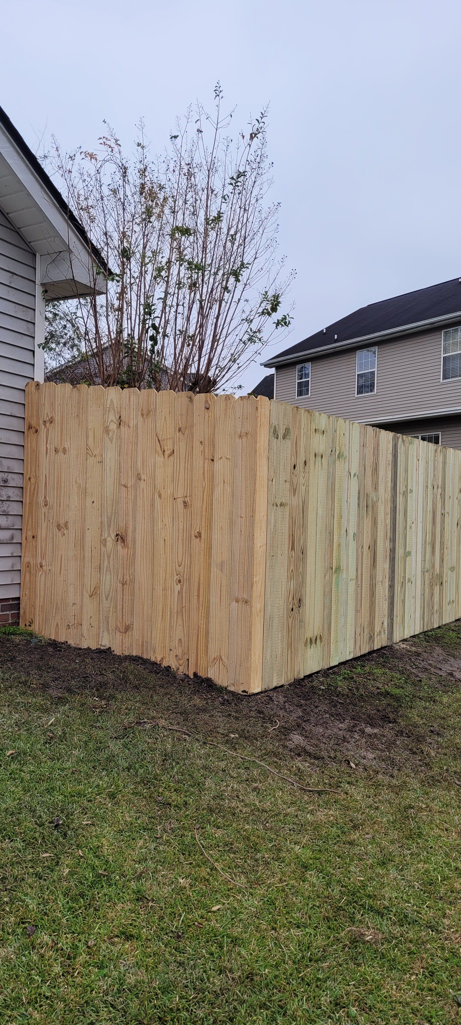 A wooden fence is in the backyard of a house.