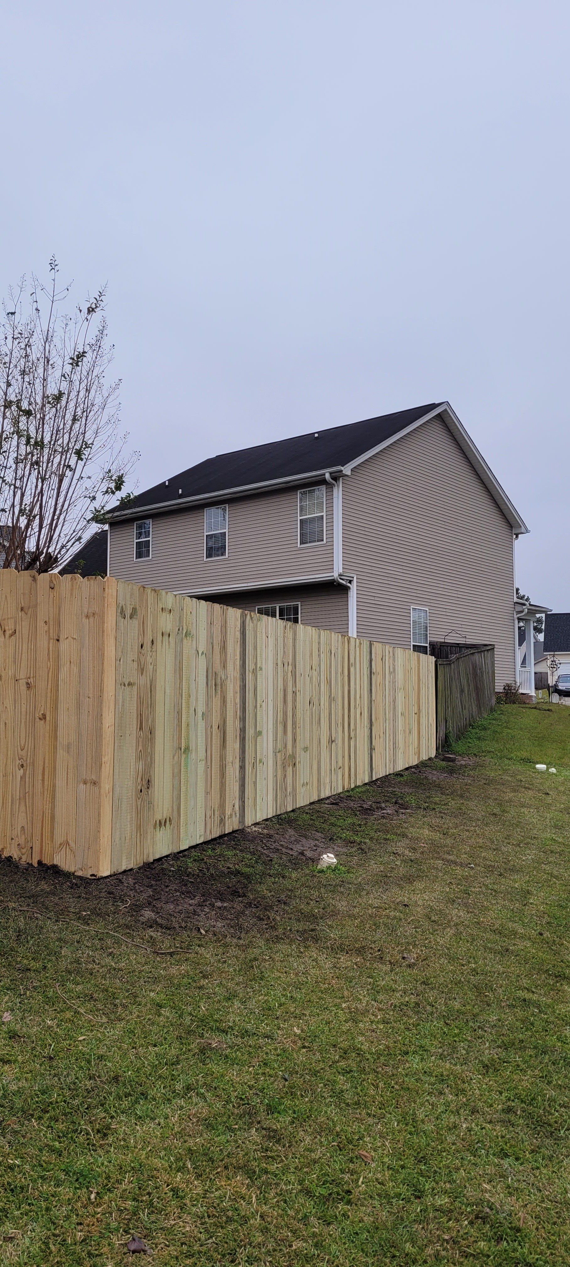 A wooden fence is sitting in front of a house.