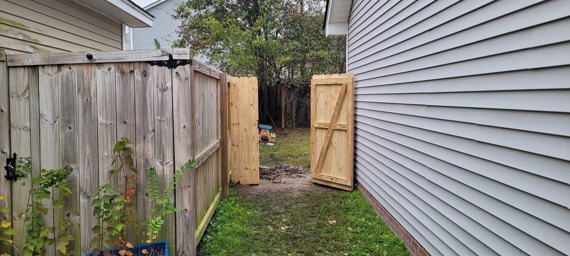 A wooden fence with a gate in the backyard of a house.