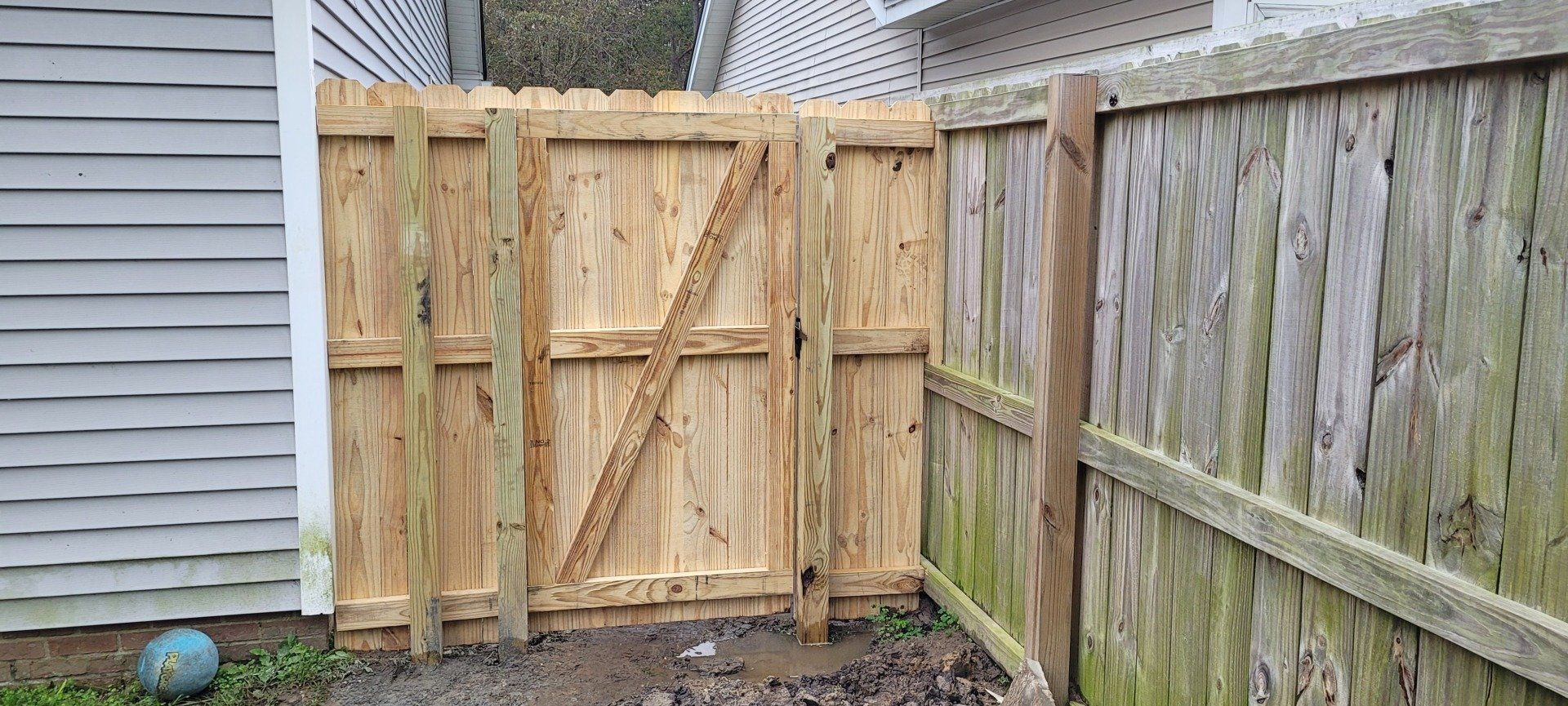 A wooden fence with a gate in the backyard of a house.