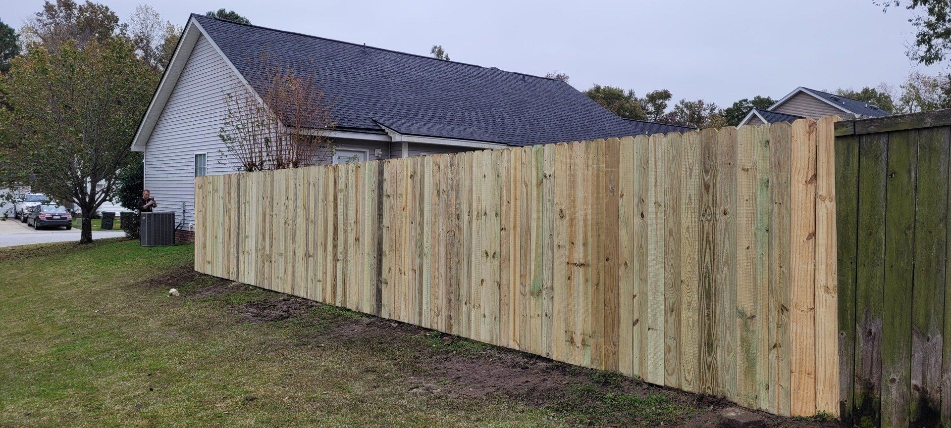 A wooden fence is sitting in front of a house.