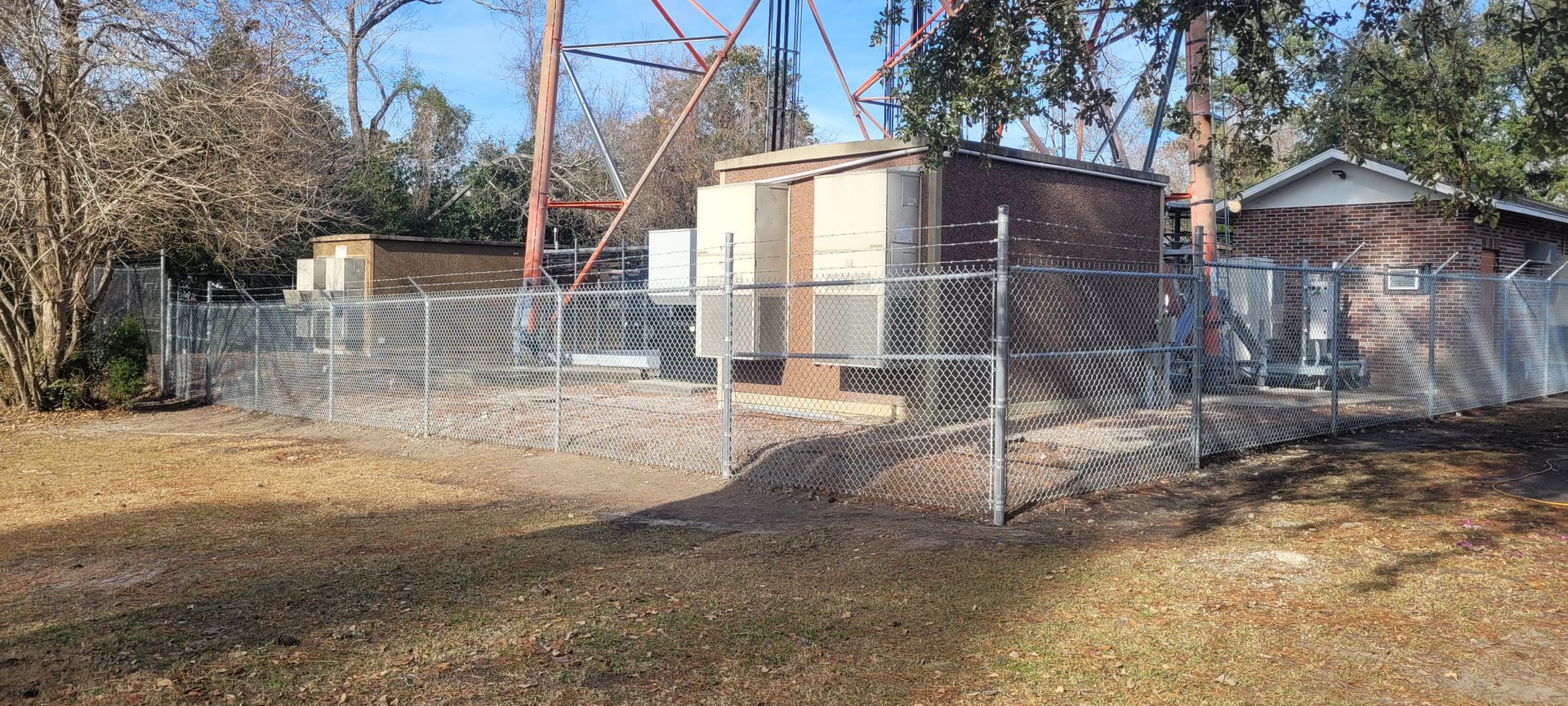 A chain link fence surrounds a building in a yard.