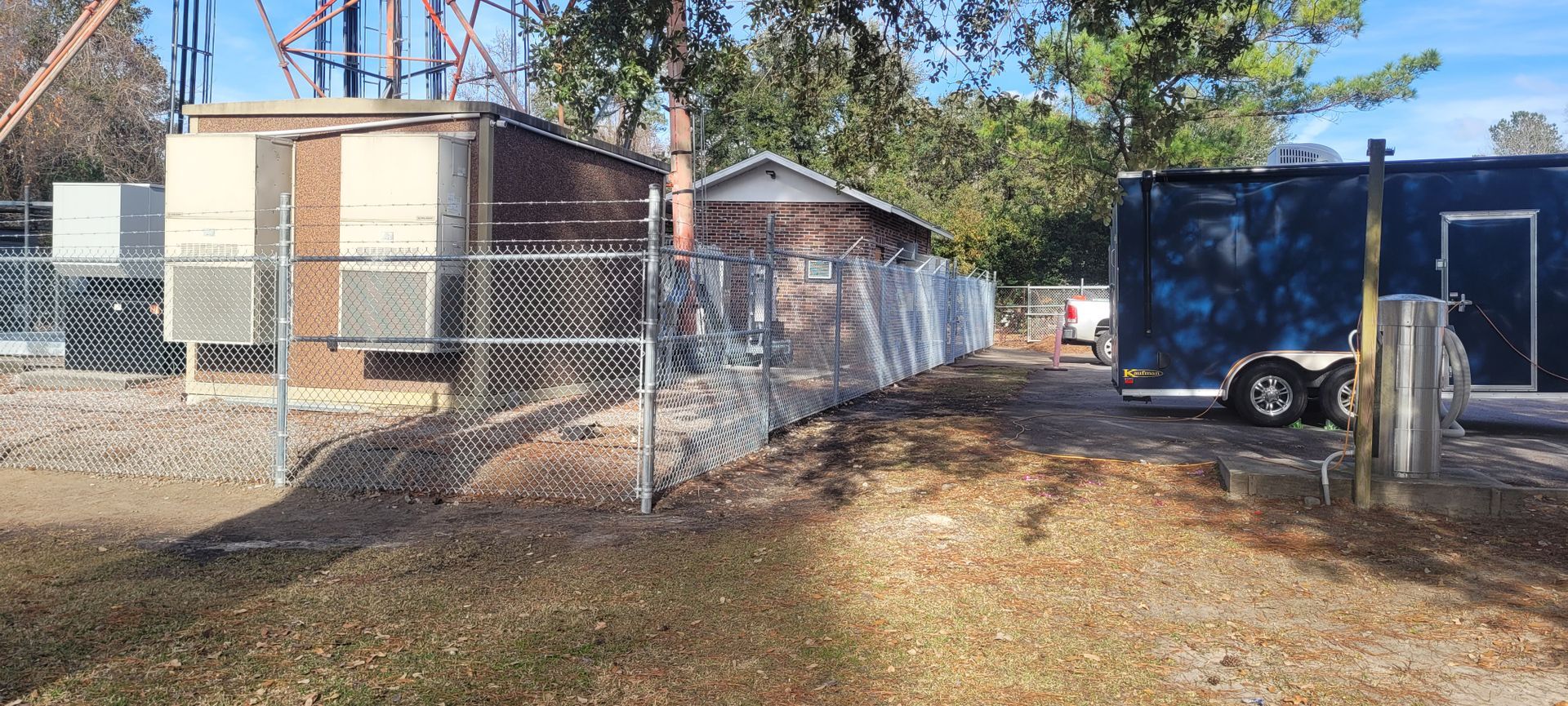 A chain link fence surrounds a building and a trailer.