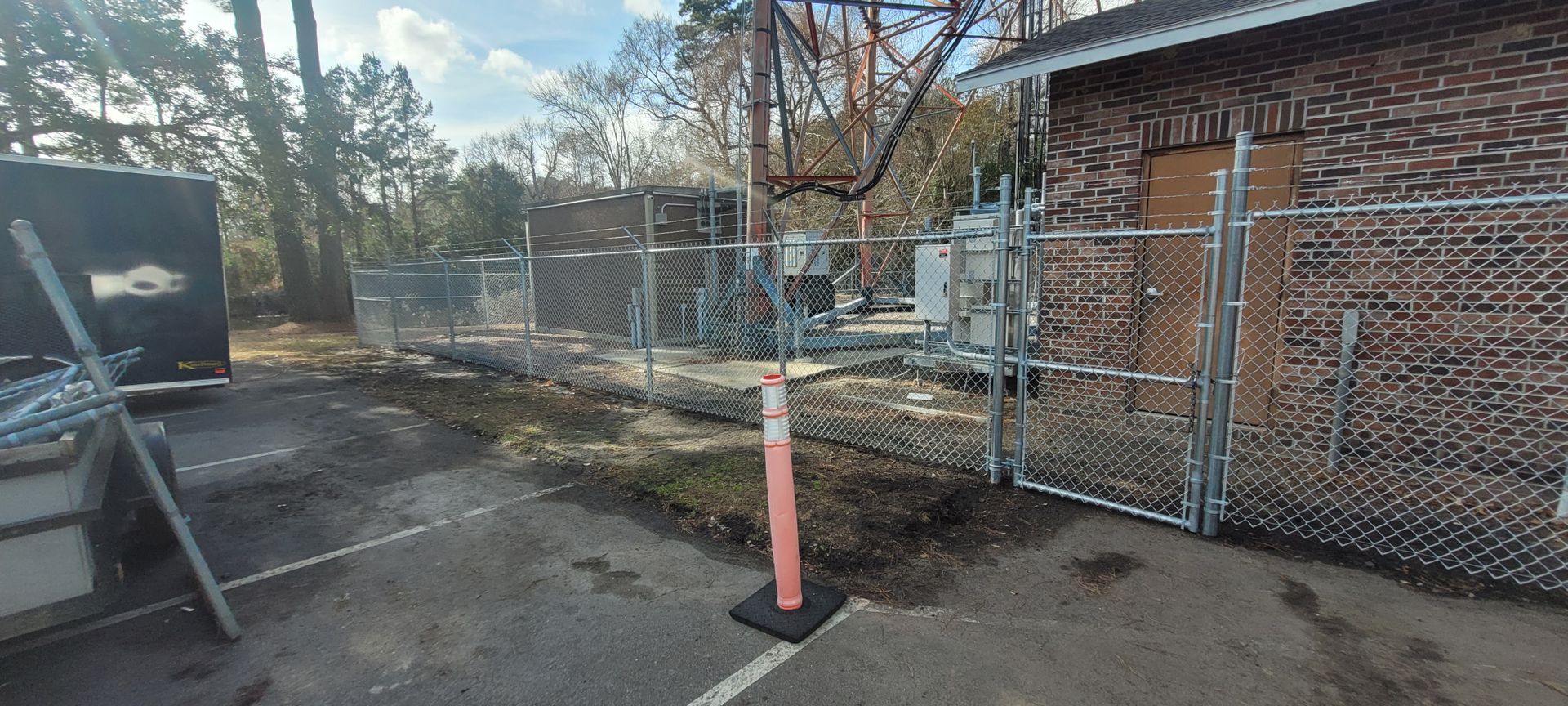 A chain link fence is surrounding a brick building in a parking lot.