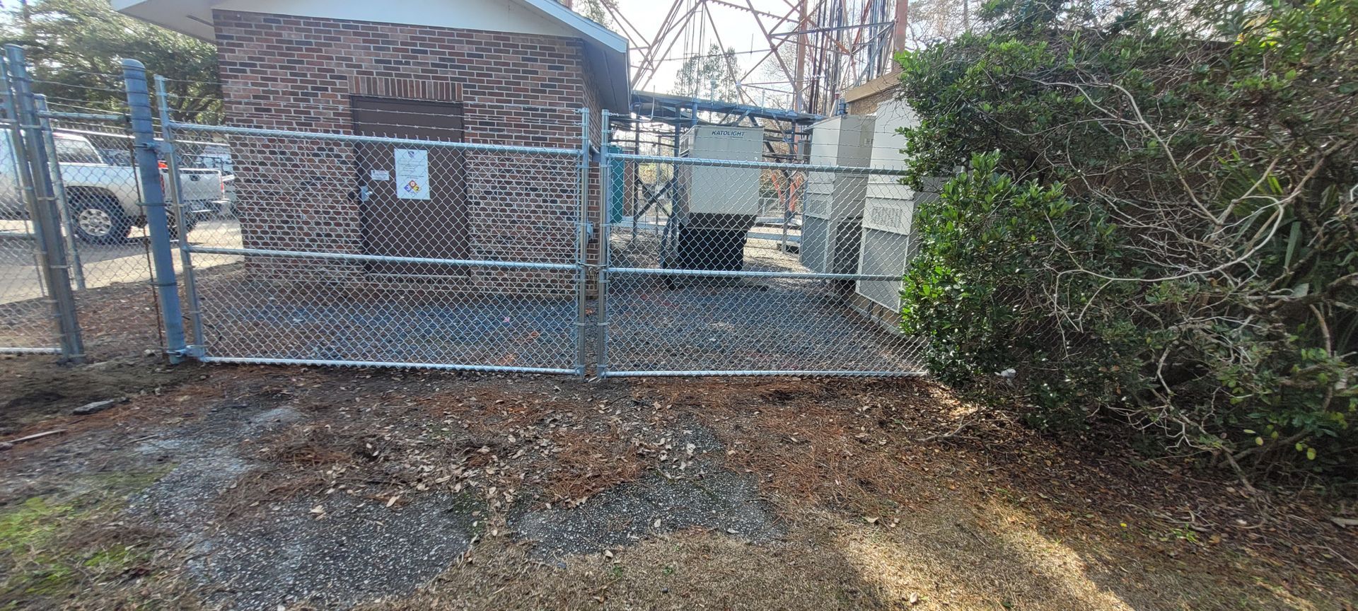A chain link fence is surrounding a shed in a yard.